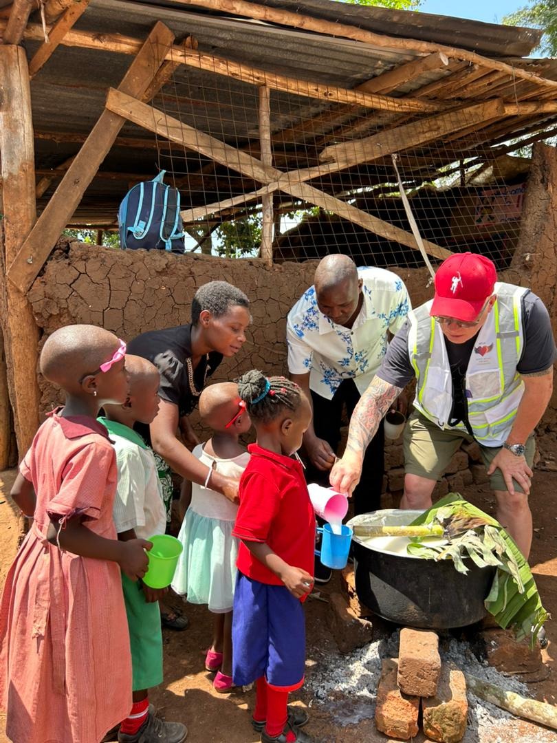 Visitors serving porridge to children